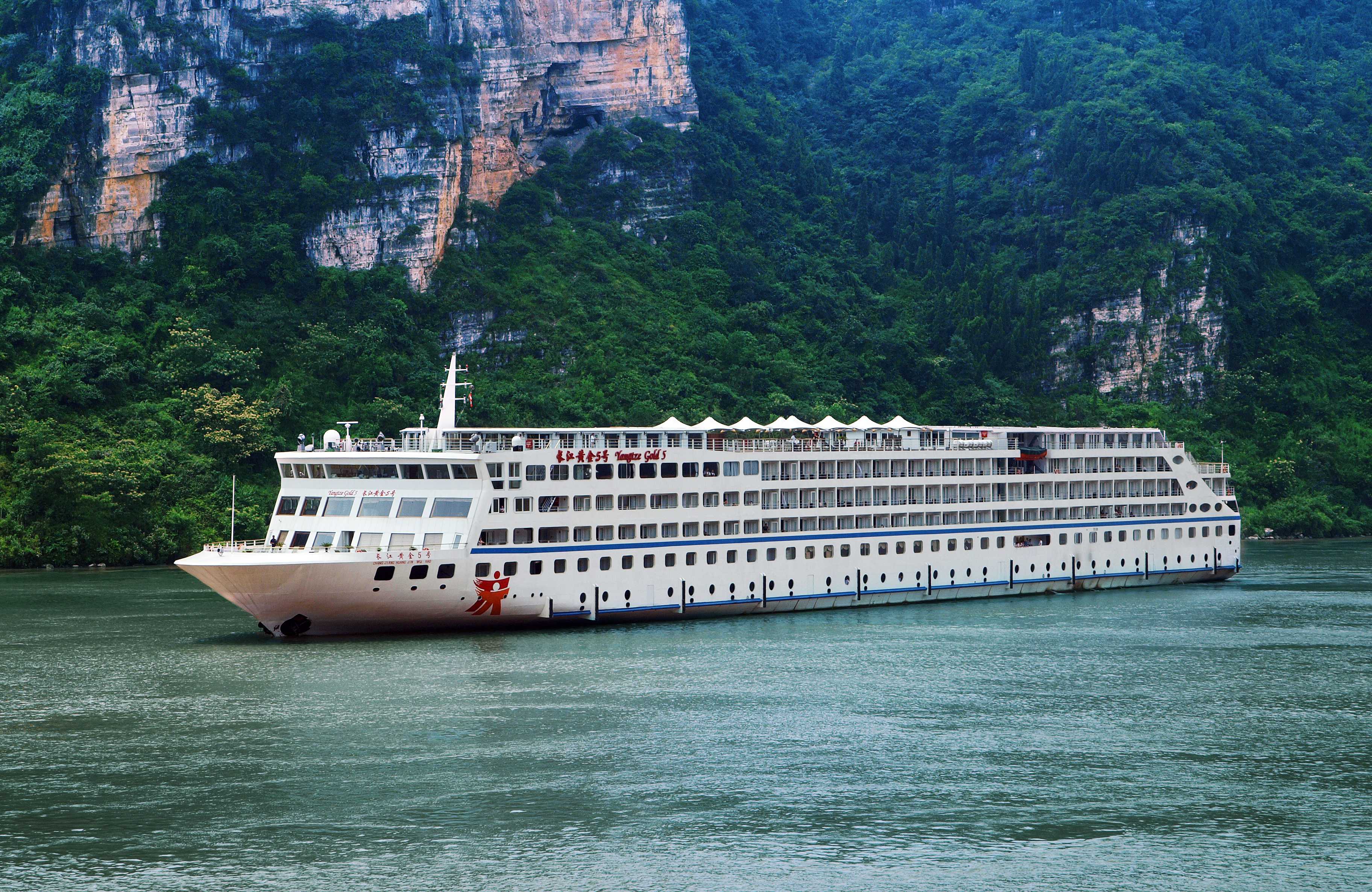 豪华邮轮停泊在江边，船体洁白，现代化设计，江水清澈，背景青山如画