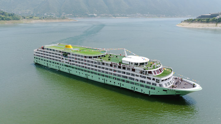 邮轮餐厅内部，圆桌座椅整齐排列，灯光温馨，窗外江景如画